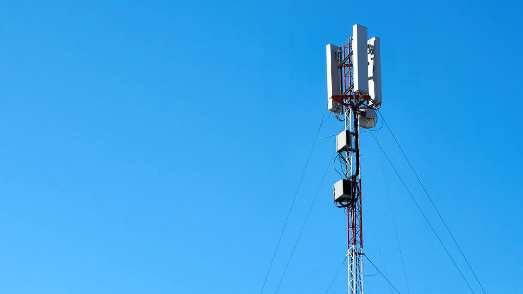 Cellular communications tower against blue sky, illustrative photo
